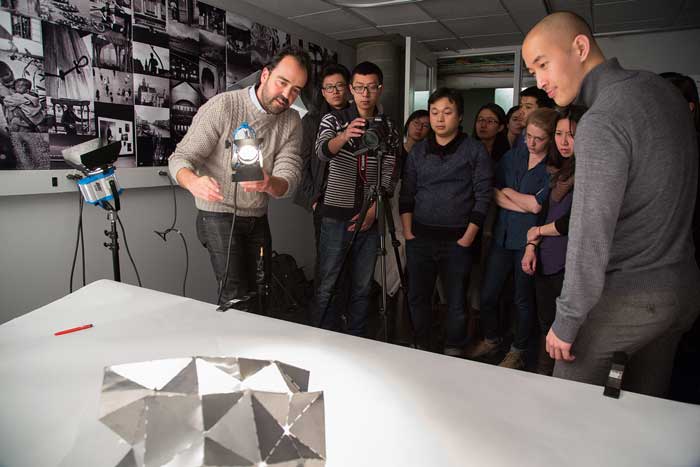 Students and faculty gather around a camera and look at an object on the table.