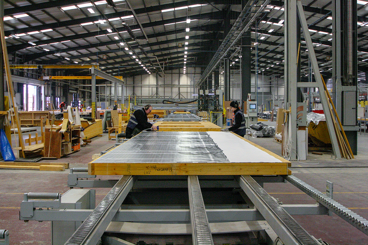 Inside the OSM factory: Builders installing a vapor barrier on what will become an exterior wall panel.