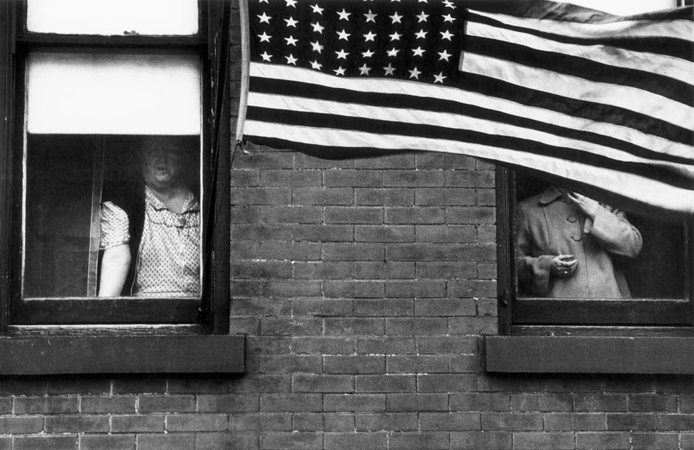 Robert Frank's photograph of two people watching a parade, their faces partially covered by an American flag