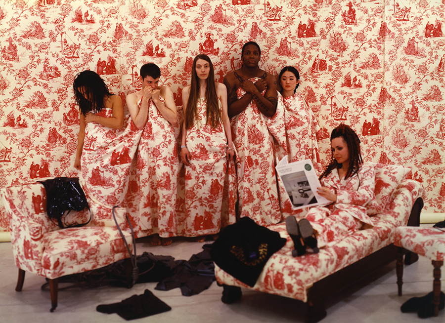 Six people in wallpaper-patterned cloth standing against the same wallpaper in a room installation in Renée Green, Mise-en-scène: Commemorative Toile, 1992–94.