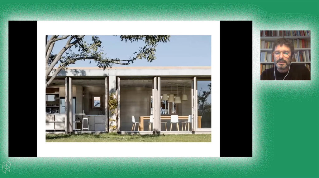 Screenshot from a virtual event. Roger Tudó Galí appears in a small square on the right and wears a black shirt and glasses. A larger rectangle contains his PowerPoint presentation, which shows a house from the outside, with large windows and a tree overhead. Roger and the PowerPoint are surrounded by a green background.