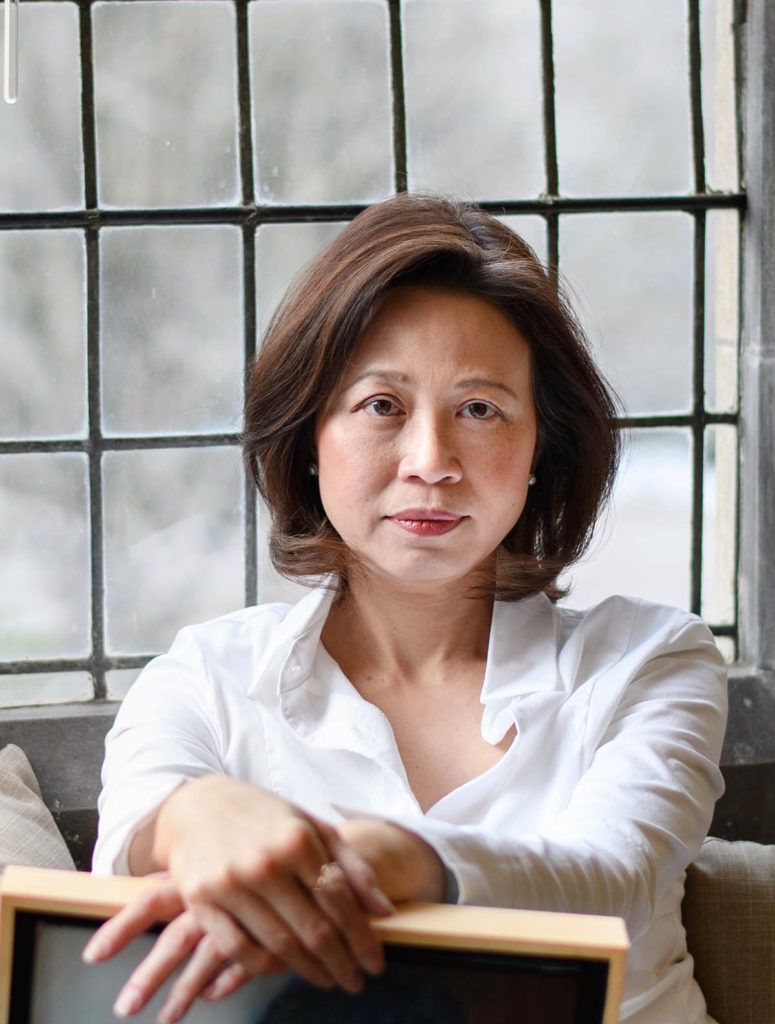 Headshot of Anne Anlin Cheng, who wears a white collared shirt and has chin-length brown hair. She sits in front of a window.
