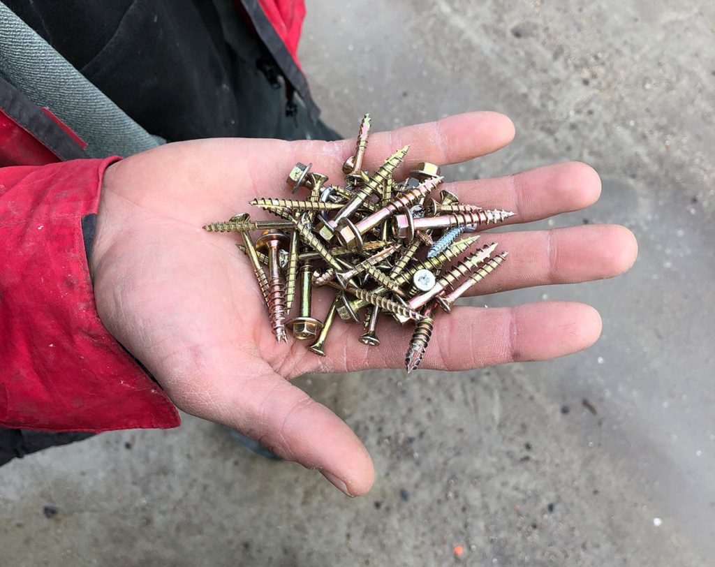 An open hand holds a pile of screws.