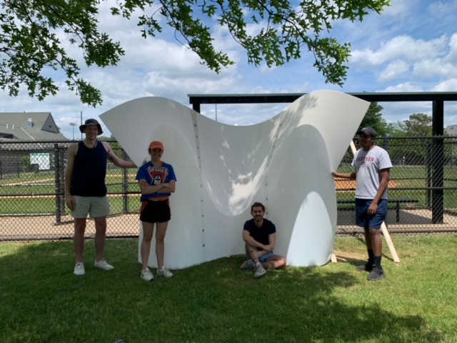 Four students pose with a piece of the pavilion.