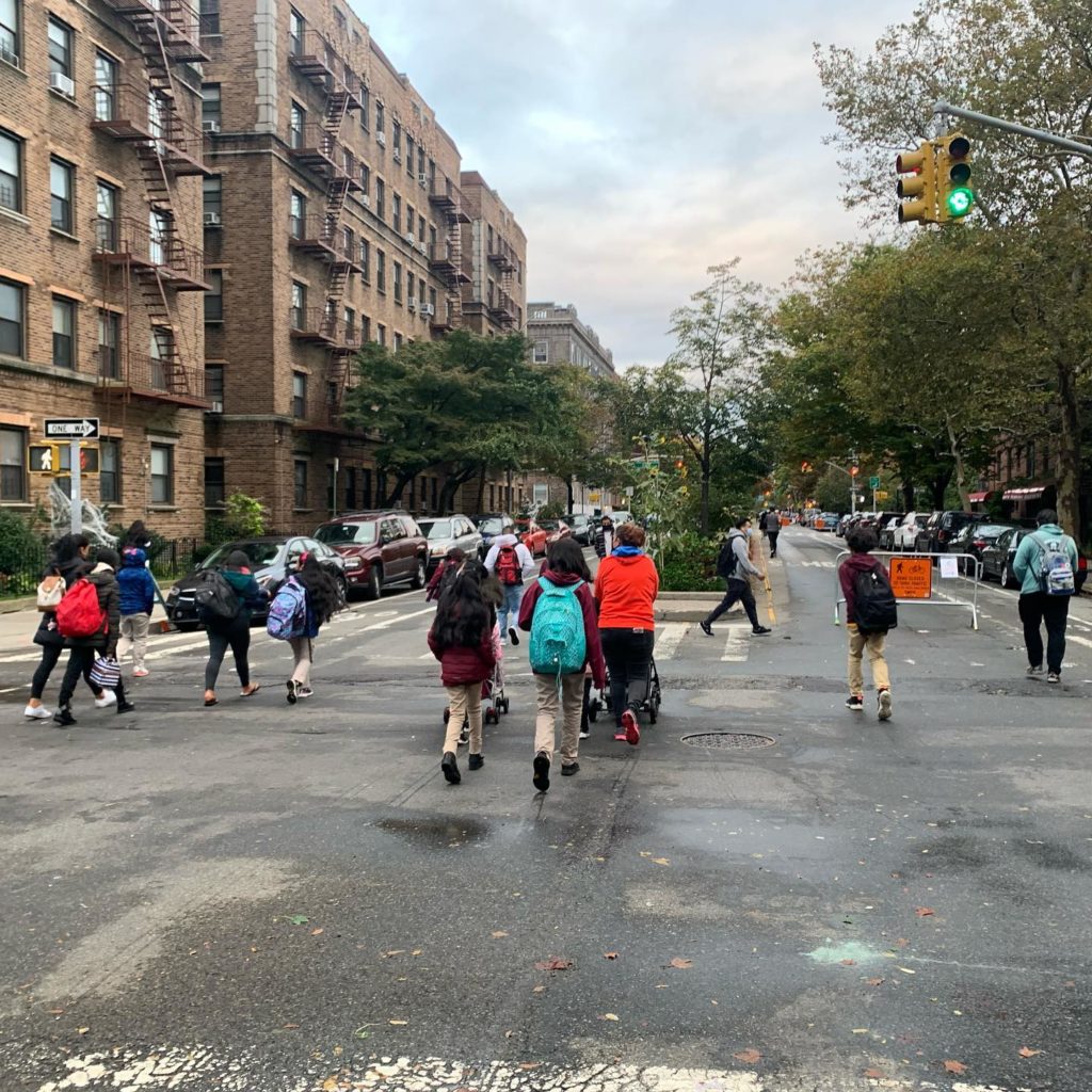 Image of several elementary-aged school students walking to school on blocked-off street in Jackson Heights 