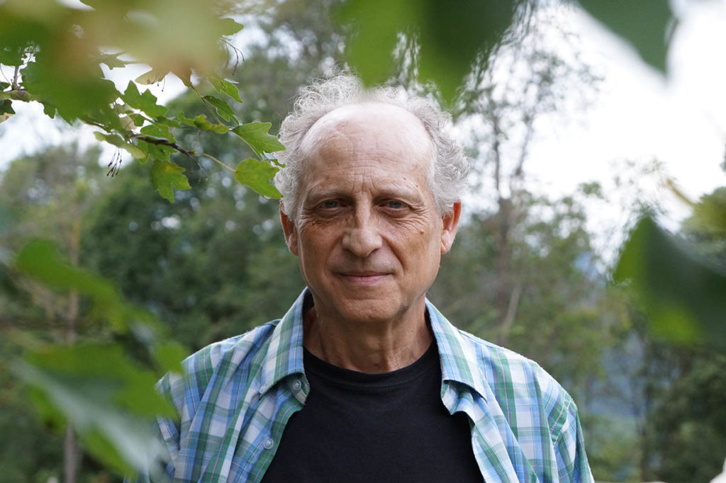 Joan Nogué stands outdoors, surrounded by leaves.