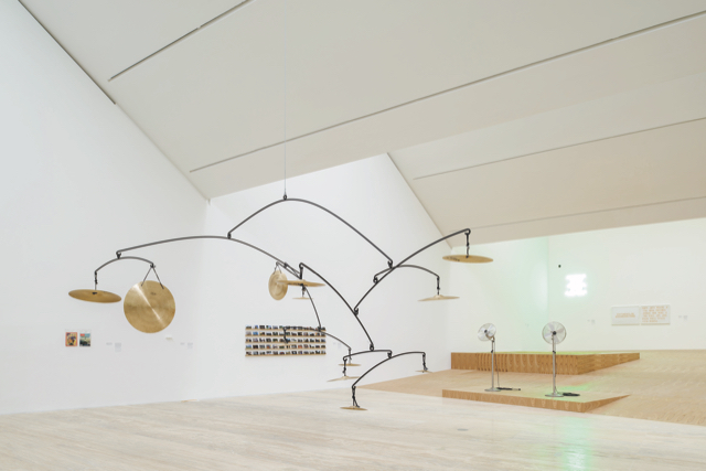 An image of an installation by Escobedo. In the middle of a light coloured room wth an undulating ceiling is a skeletal sculpture.
