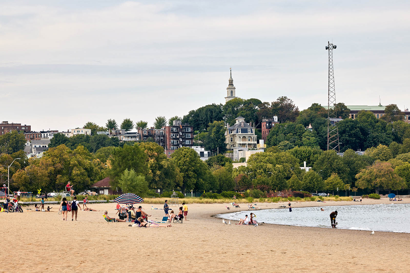 Photo of people on a beach with houses in a background
