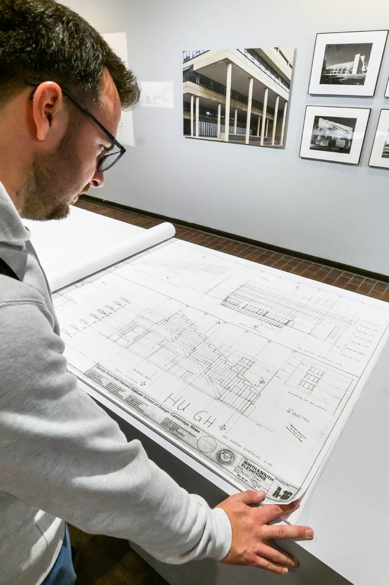 A person looking at a diplay table with facimile construction documents of Gund Hall