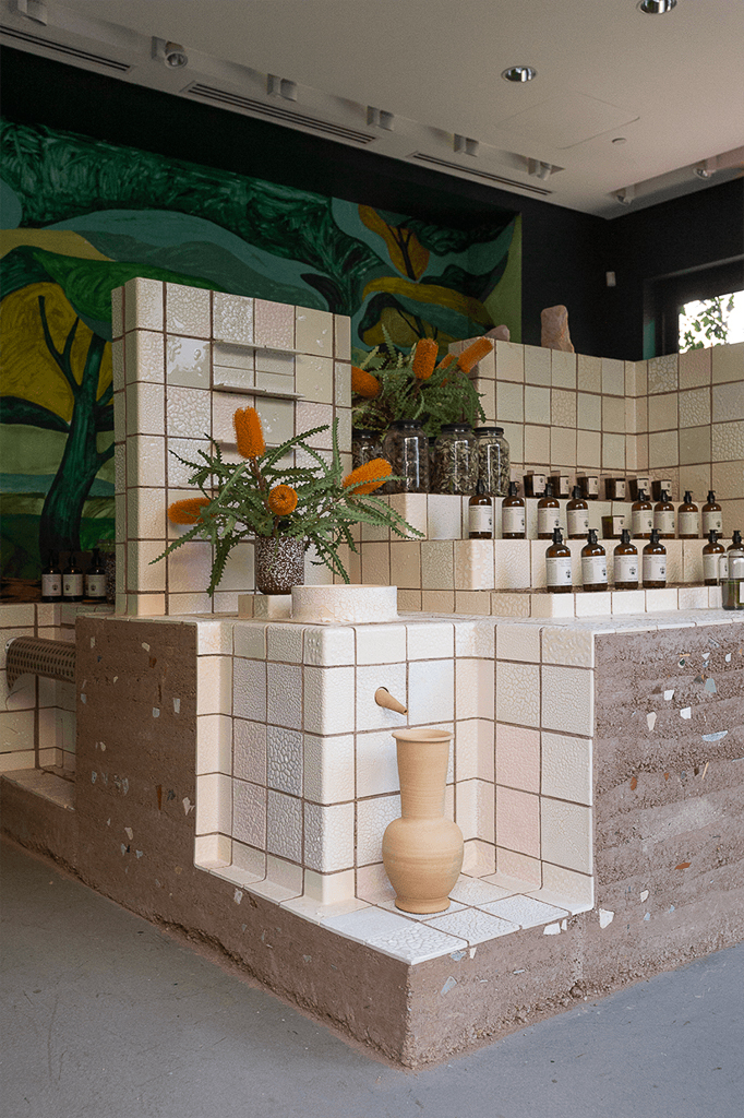 View of small wellness pop-up with labeled soap bottles and white tiled countertops.