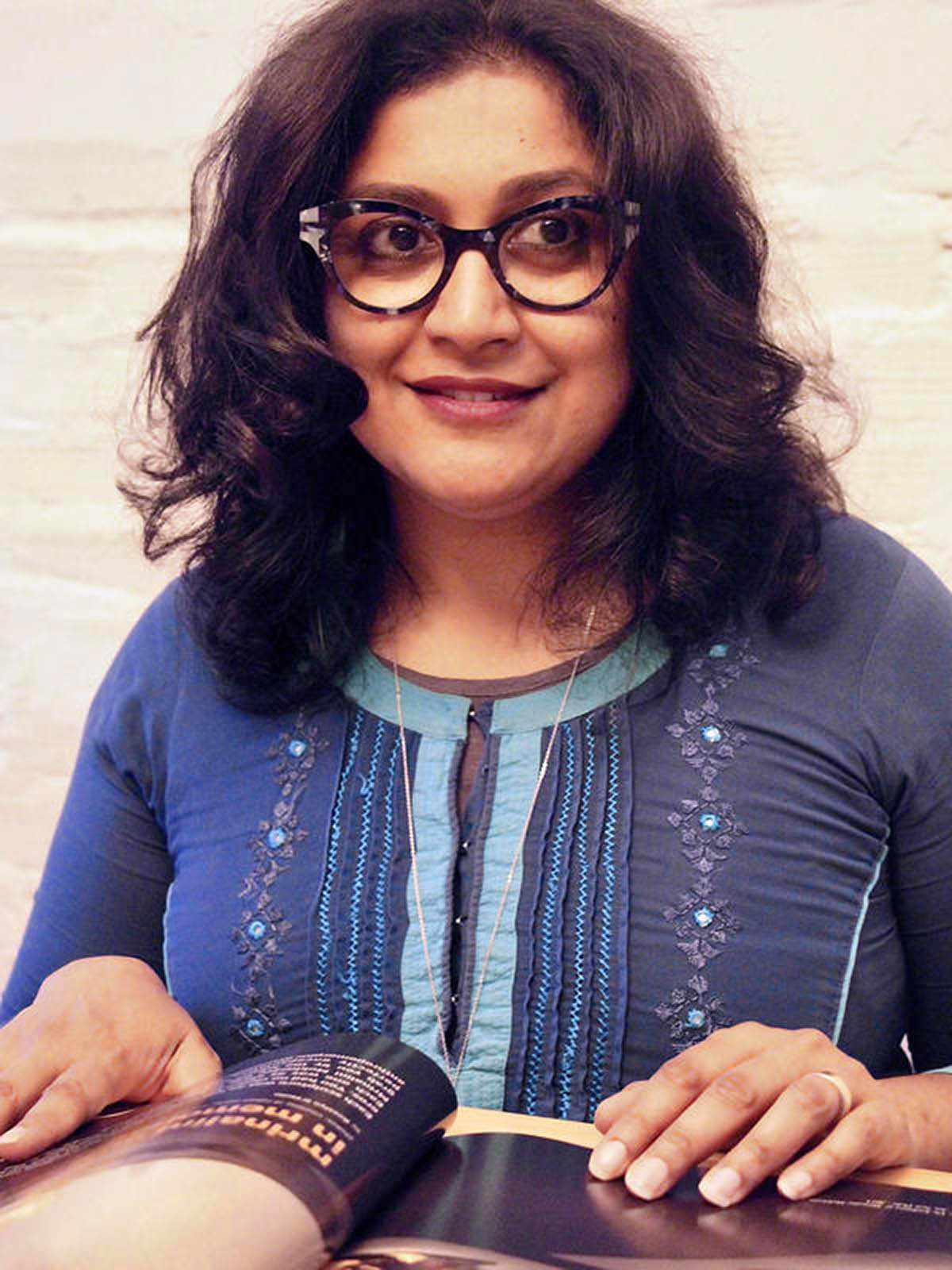 Headshot of Anooradha Iyer Siddiqi, who wears glasses and a blue shirt.