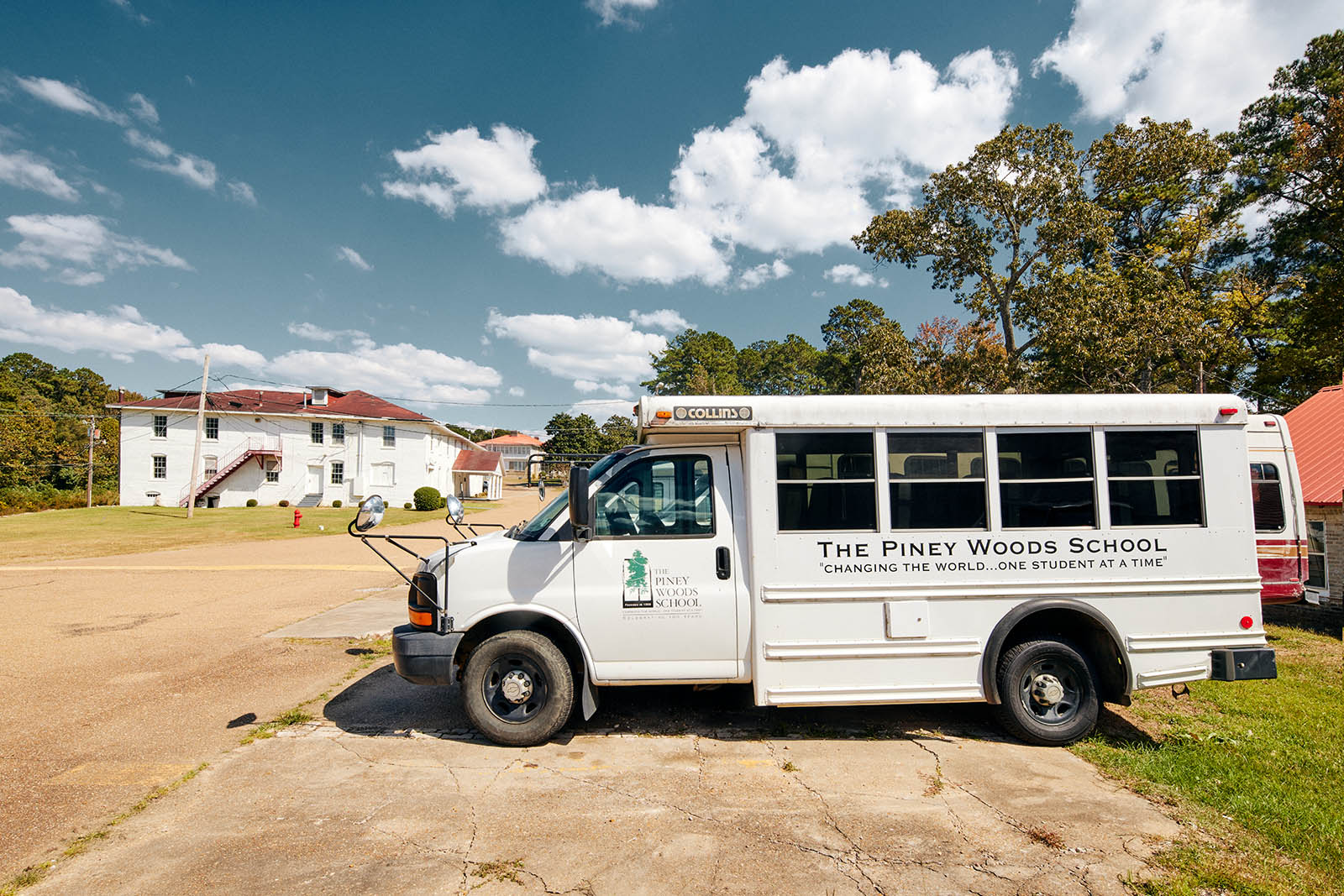Photo of a white mini school bus with words "The Piney Woods school" words on it